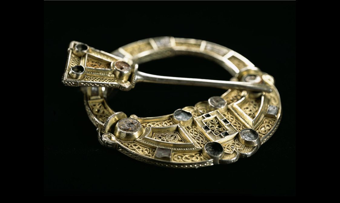 A gold circular brooch.