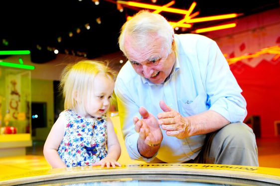 A kid and an adult engaging in an interactive conversation by the play area.