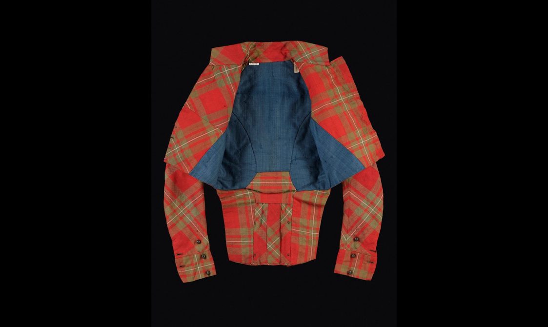 A red tartan jacket with the lapels open to show a dark blue lining.