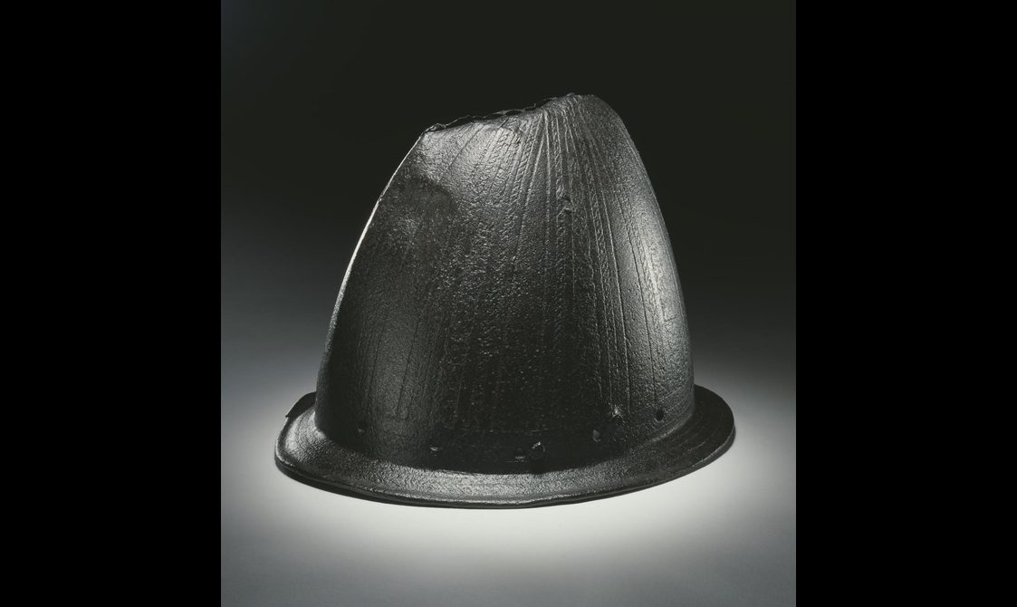 An iron helmet with a narrow rim and a slanted peak