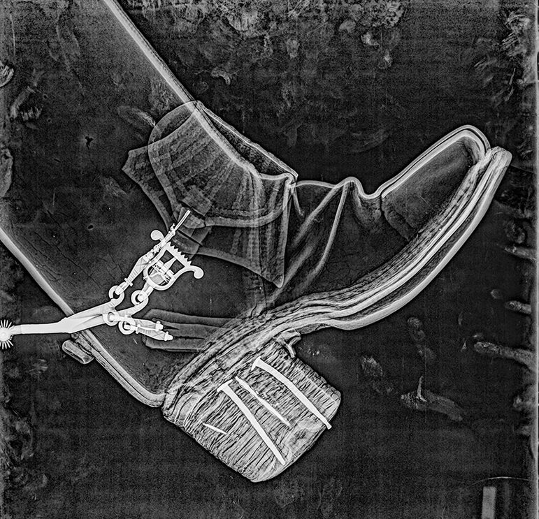 X-ray scan of a long black 17th century Jack boots against a black background.