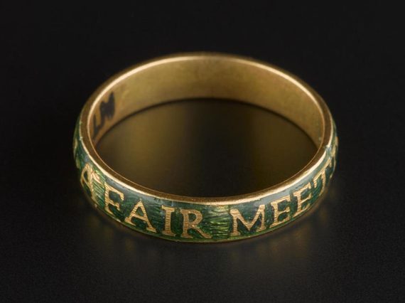 A round gold band set against black background, outer bad covered with green enamel and gold inscription.