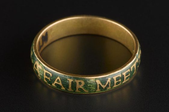 A round gold band set against black background, outer bad covered with green enamel and gold inscription.