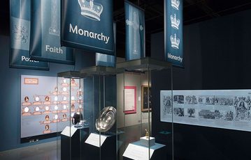 Objects on display in the Bonnie Prince Charlie and the Jacobites exhibition. The objects are in three display cases underneath banners that read, "Power", "Faith", "Monarchy".