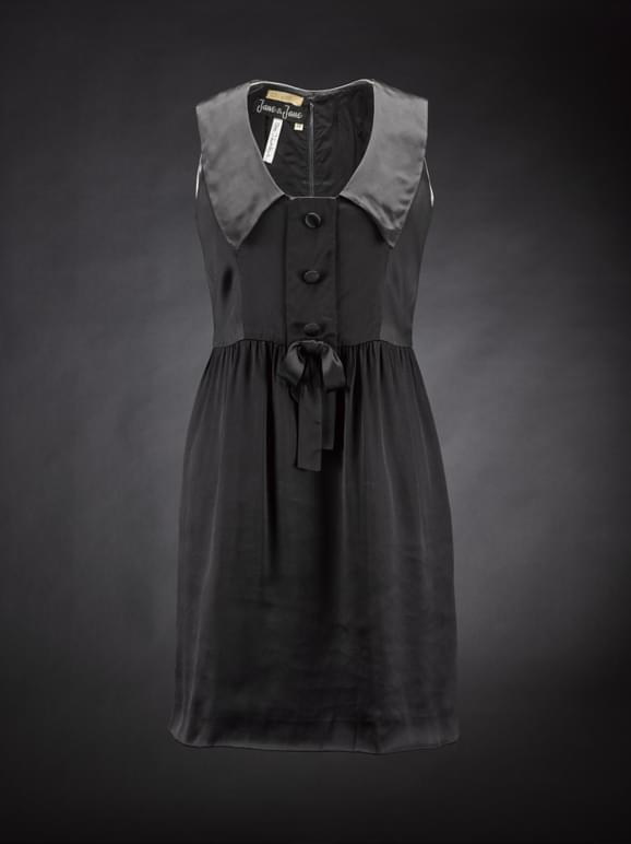 A black satin mini dress with a large collar, buttons at the bust, and a small bow at the waist.