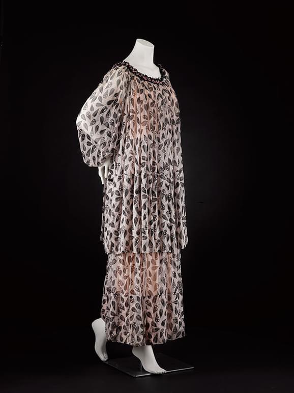 A mannequin wearing a long chiffon dress with a light pink and black pattern.