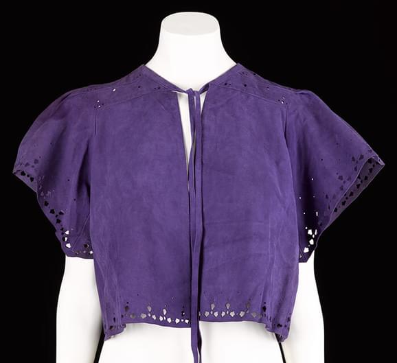 A mannequin wearing a purple suede short sleeved shirt with a tie at the neck.