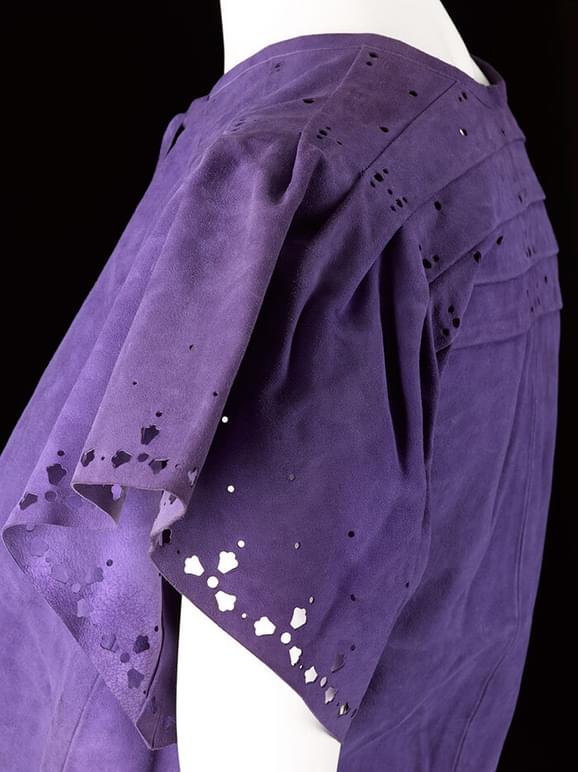 A detail of a mannequin wearing a purple suede short sleeved shirt.