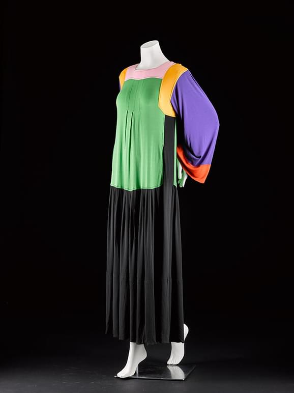 A mannequin wearing a long draped dress featuring bold block colours against black.