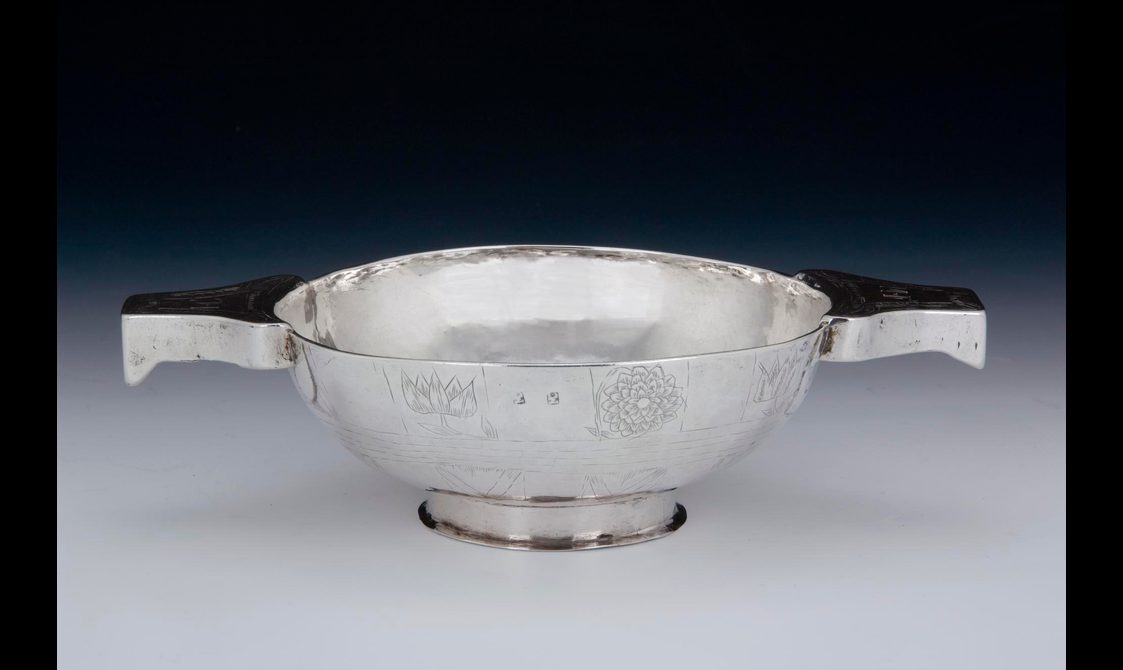A shallow silver bowl with handles on each side