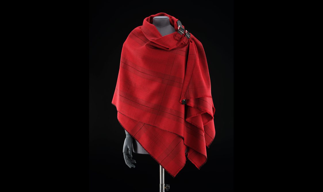 A mannequin wearing a red tartan shawl.