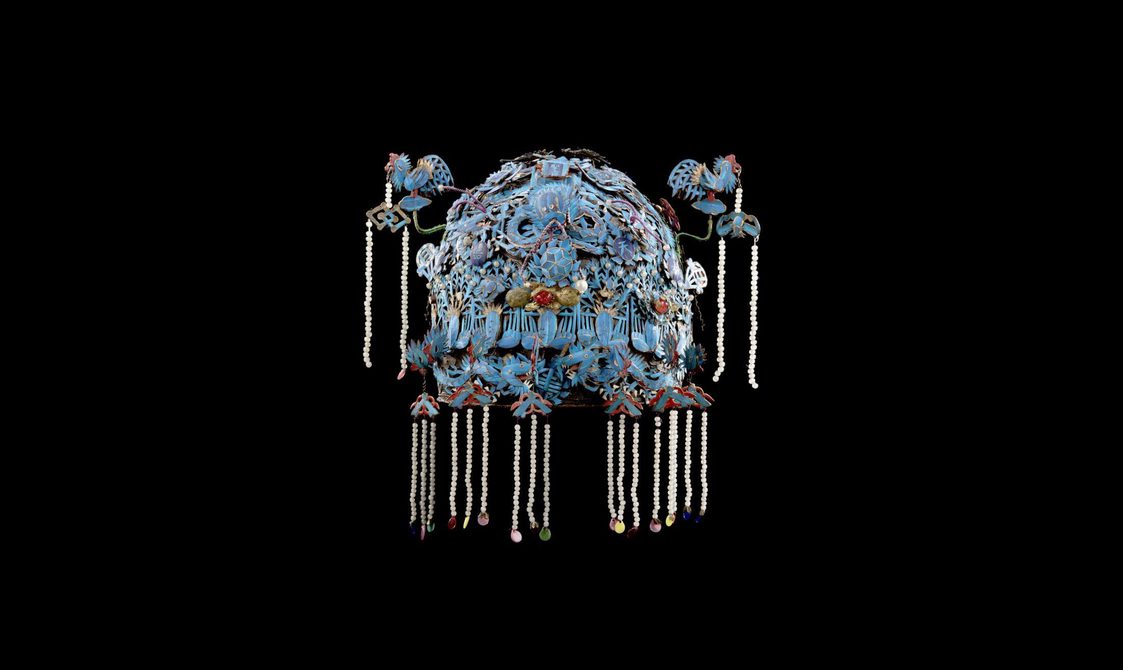A blue Chinese headdress decorated with feathers from kingfisher birds.
