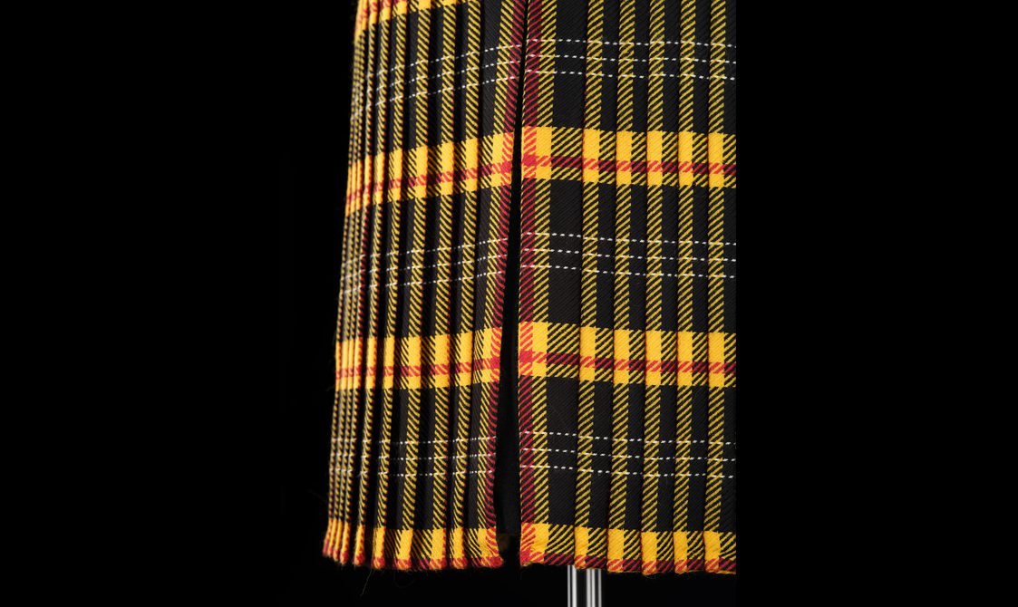 Detail of a yellow and black tartan kilt.