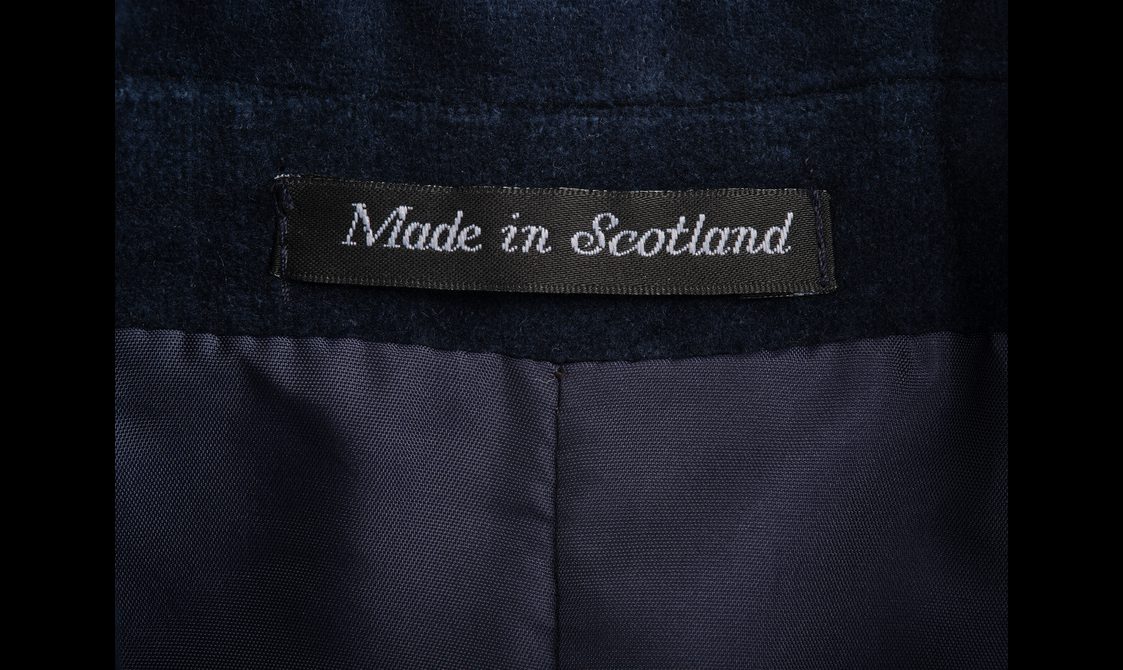 A detail of a velvet jacket showing a 'Made in Scotland' label.