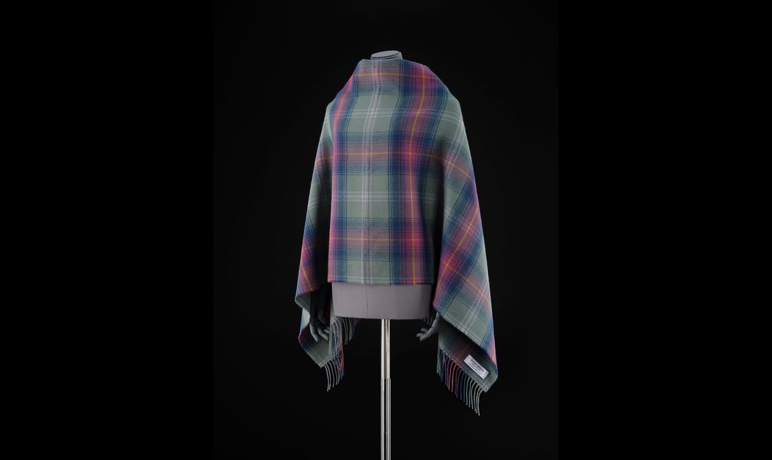 A mannequin wearing a purple, pink, and green tartan shawl.