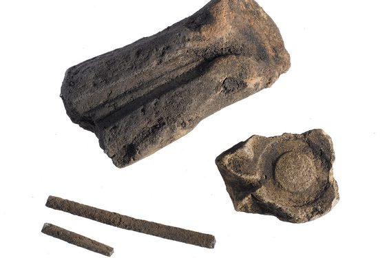 Two large chunks of stone, one with a long skinny indentation and another with a ring-like indentation. Two other skinny pieces of stone alongside.