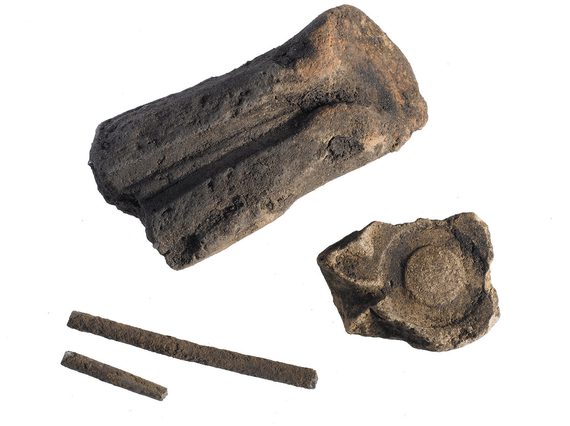 Two large chunks of stone, one with a long skinny indentation and another with a ring-like indentation. Two other skinny pieces of stone alongside.