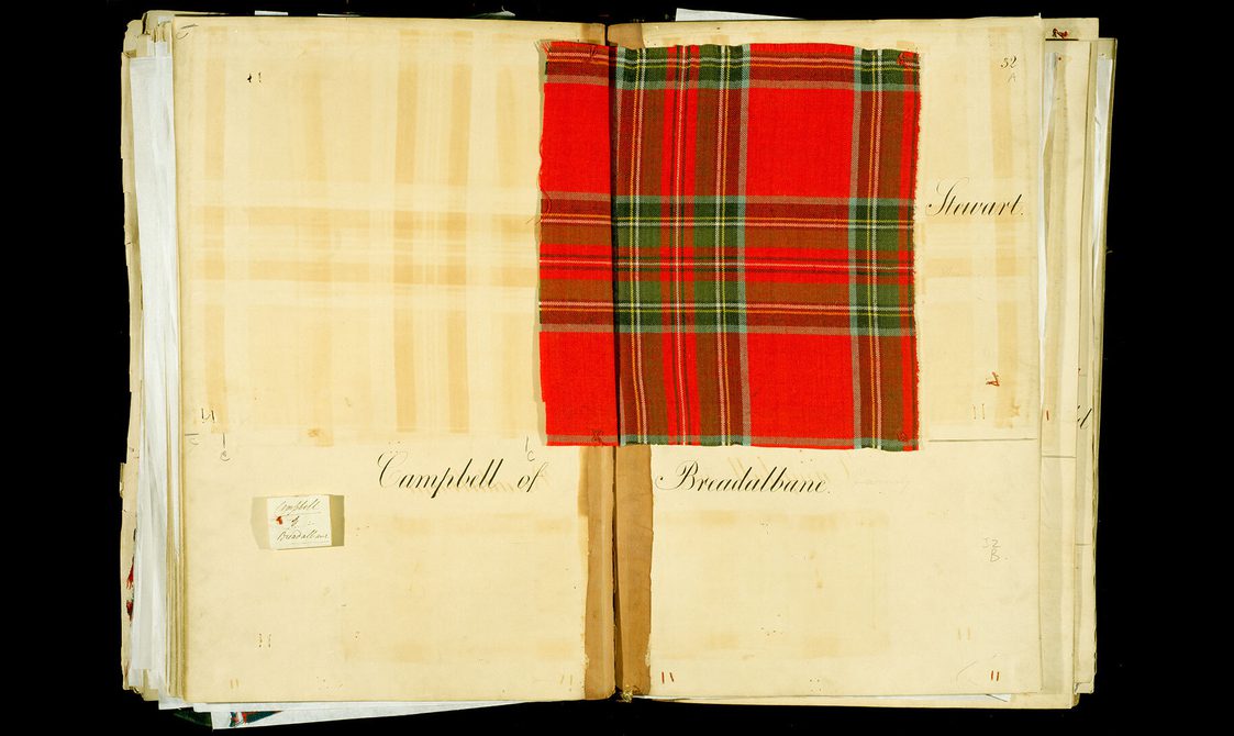 A notebook open showing a square of red tartan. Written on the pages are the notes, "Stewart" and "Campbells of Breadalbane".