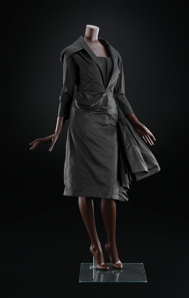A mannequin wearing a black knee length dress with a large collar and three quarter length sleeves