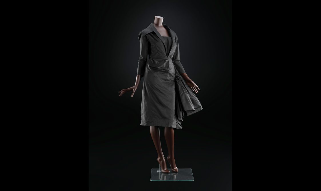 A mannequin wearing a black cocktail dress with 3/4 length sleeves and a large collar.