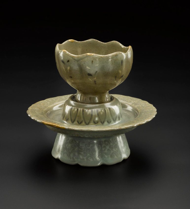 A light green-brown stoneware cup and stand shaped like a lotus flower.