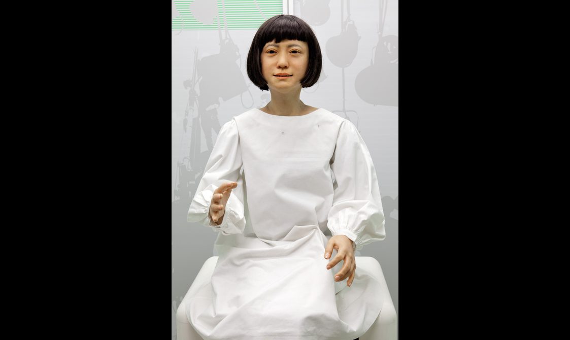 A robot that looks like a human being dresses in a white robe.