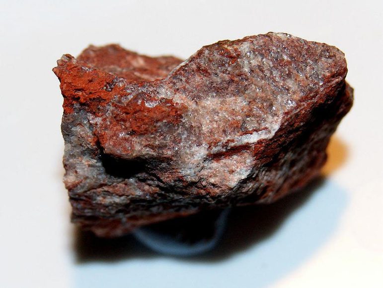 A brown and red rock sitting on a white background