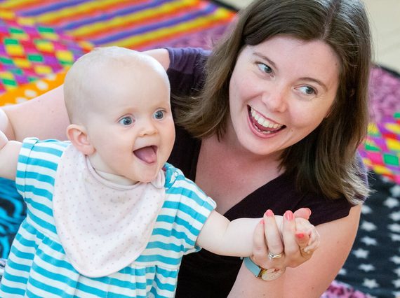 Woman and baby in arms sitting on the floor on a checked carpet.