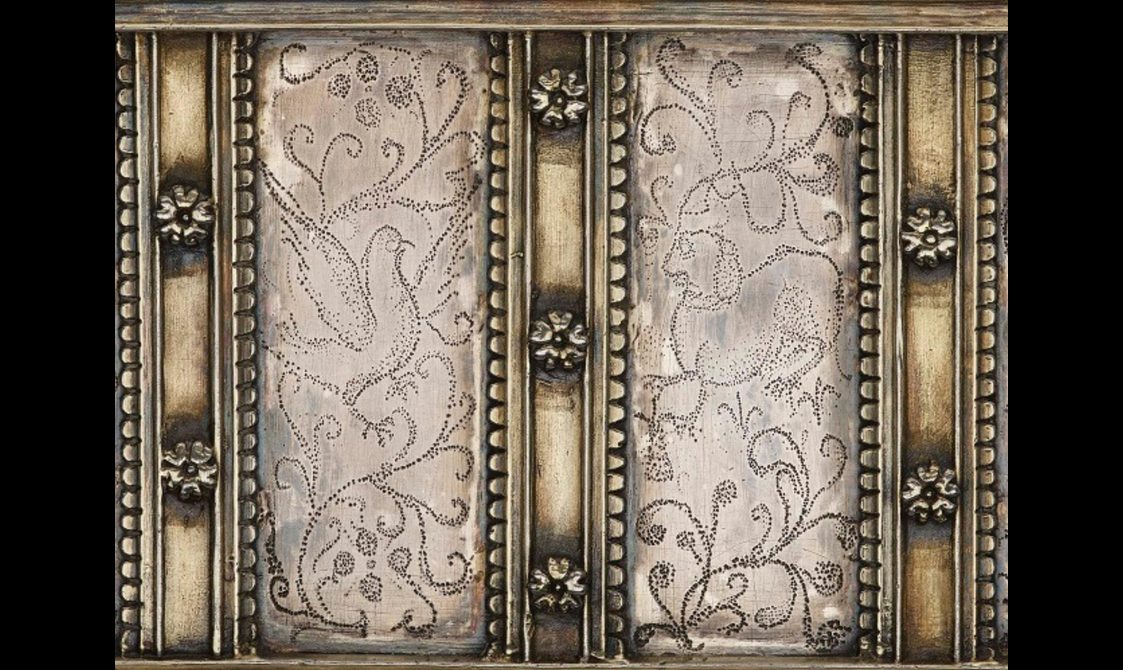Closeup of pin-pricked designs on the casket's side containing animals and branch motifs.