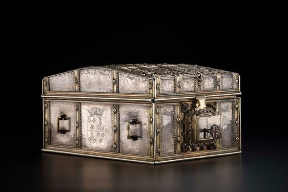 Ornate silver chest pointed at diagonally to view two sides at once. A heavy lock guards it and a coat of arms is inscribed on one side.