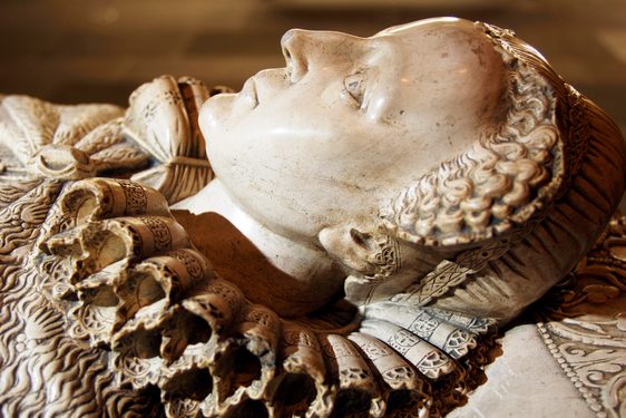Detail of a marble tomb, showing a female head with ruffle collar.