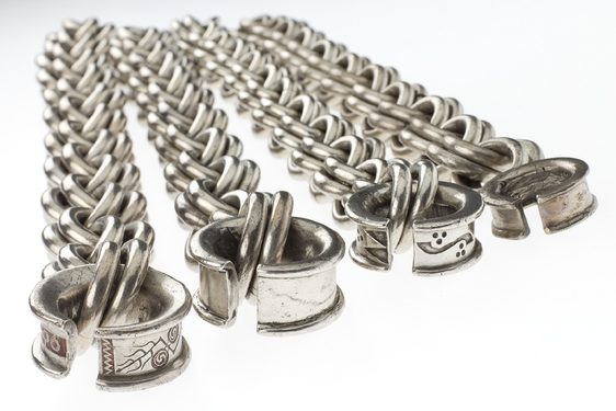 Four large horizontally laid silver chains with geometric and curve-shaped carvings