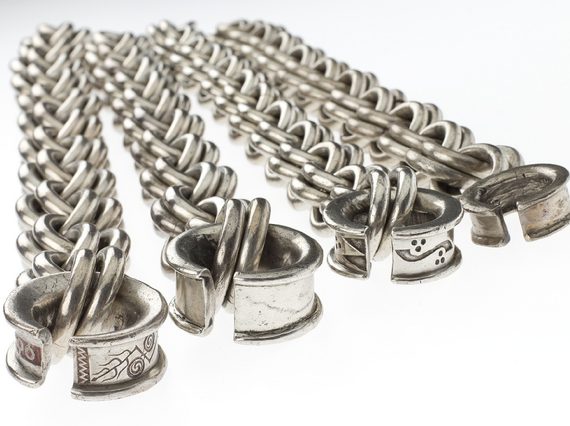 Four large horizontally laid silver chains with geometric and curve-shaped carvings