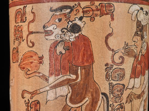 Ancient Mayan vase depicting a detailed illustration of a smoking monkey and human figures, adorned with intricate glyphs and traditional motifs.