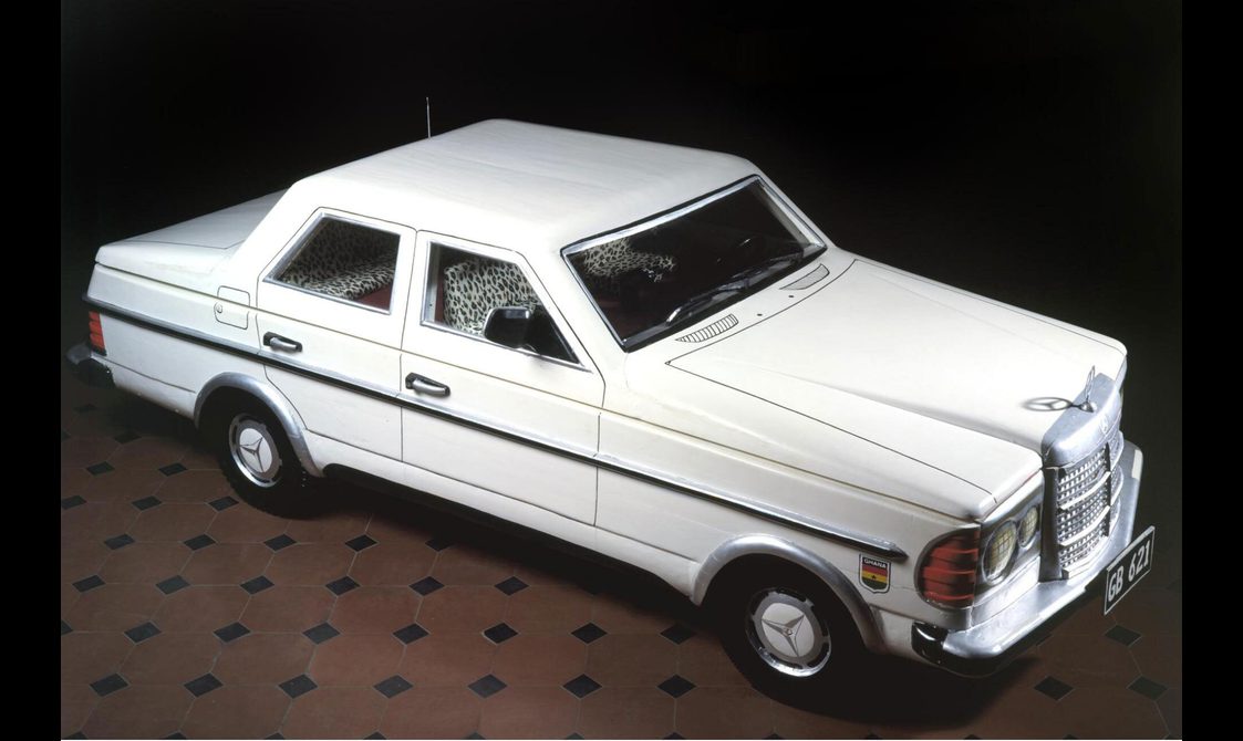 A coffin in the shape of a white Mercedes-Benz car.