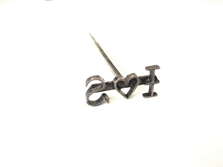 A T shaped pin like metal branding tool with reverse text I heart symbol S