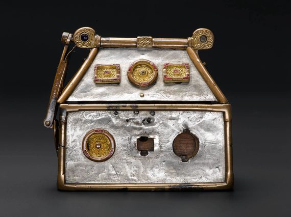 A small silver box with gold metal work along the edges. There are gold mounts of different shapes embedded on the box.