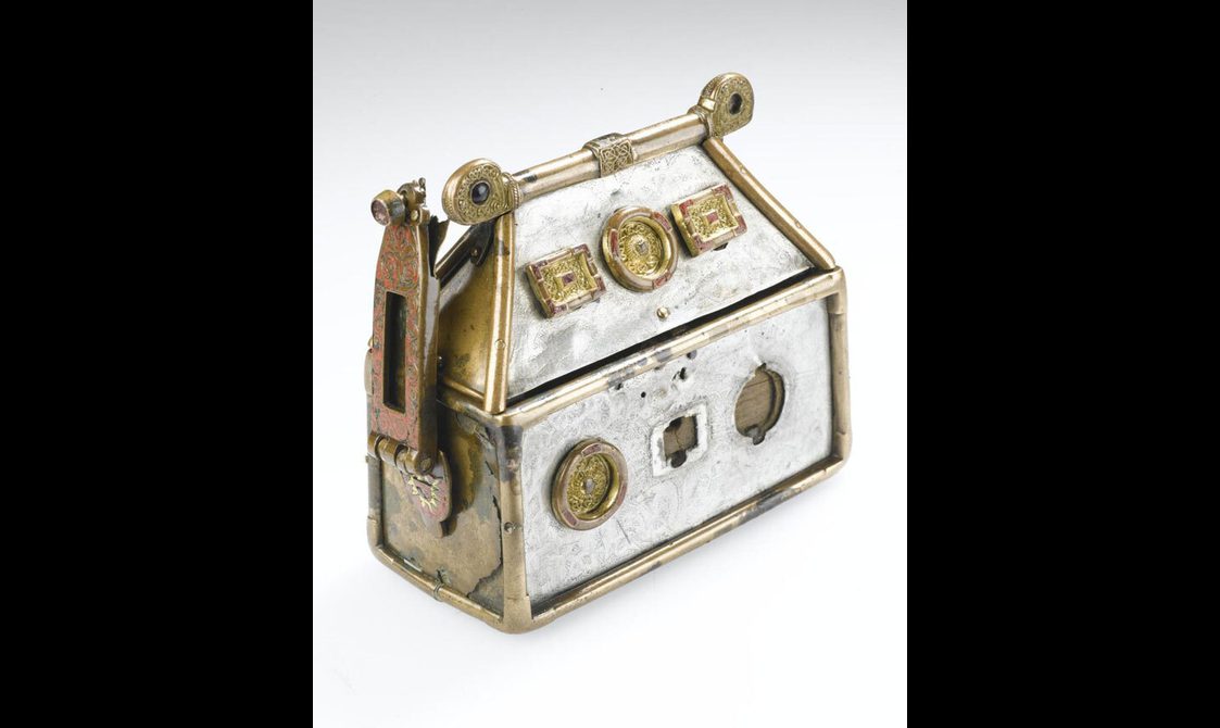 A rectangular silver box with a lid in a shape of a pitched roof, with circular and rectangular decorative motifs.