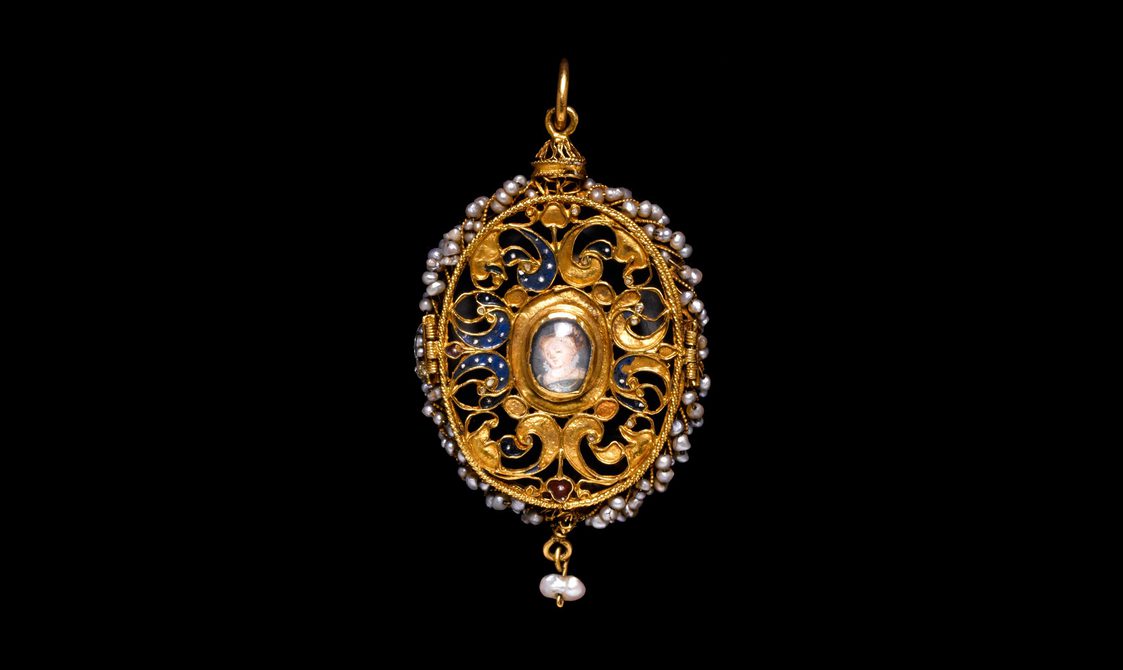 An elaborate oval gold pendant with floral pattenrs and pearls. There is a painted image of a small child in the center.