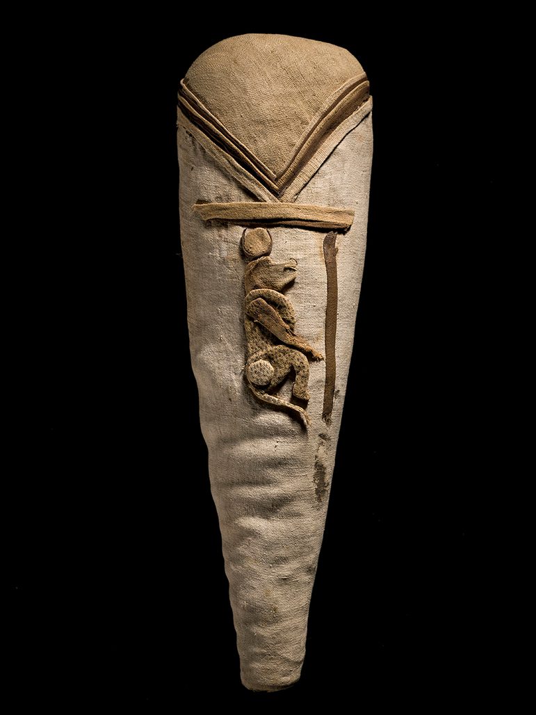 A bundle of linen wrappings with a representation of the god Thoth as a baboon wearing a sun disc in embroidered linen on the surface