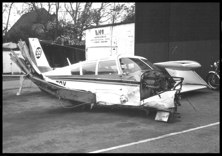 Wreckage of a Piper PA-24 'Comanche' 260B aircraft. The nose of the aircraft is missing, exposing the inner framework.