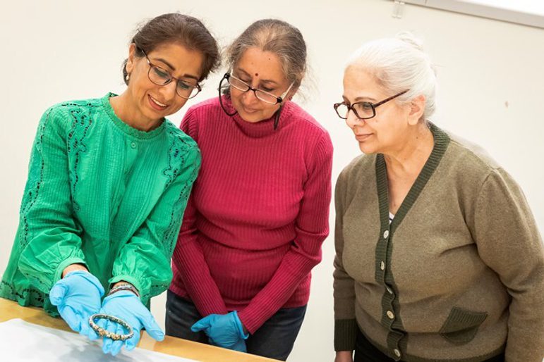 Three people admire a small golden ornament