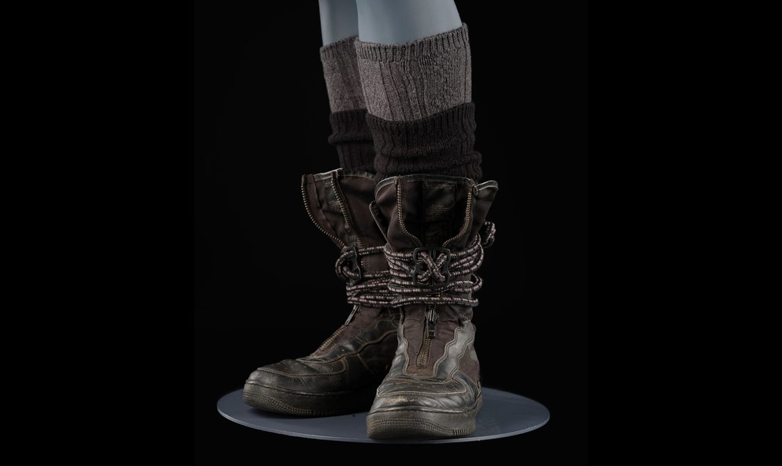A mannequin wearing knitted brown socks with brown leather boots.