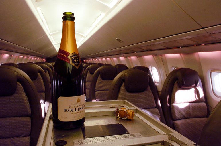 An open champagne bottle on a trolley in the middle of an aeroplane aisle.