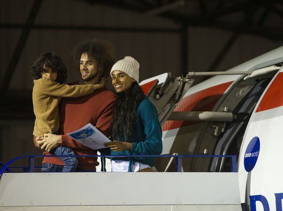 Two parents and a child standing on the boarding ramp outside a Concorde aeroplane. The child is being carried by one of the parents.