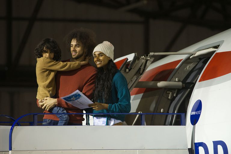 Two parents and a child standing on the boarding ramp outside a Concorde aeroplane. The child is being carried by one of the parents.