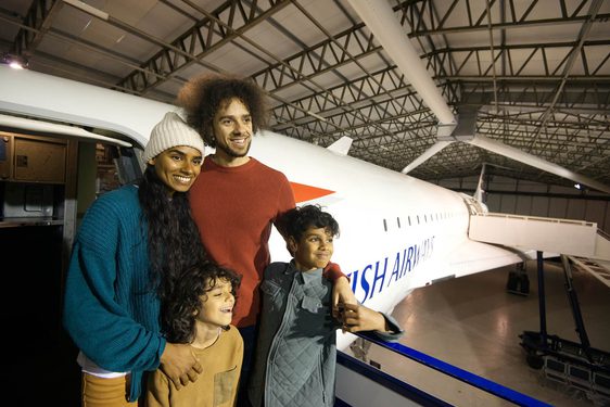 A family of four standing outside the door of a Concorde aeroplane.