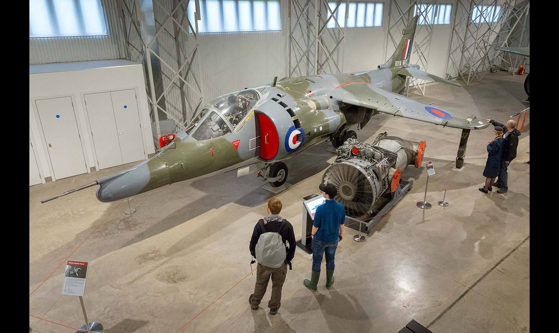 Visitors looking at a Hawker Siddeley Harrier aircraft in the Military Aviation hangar.