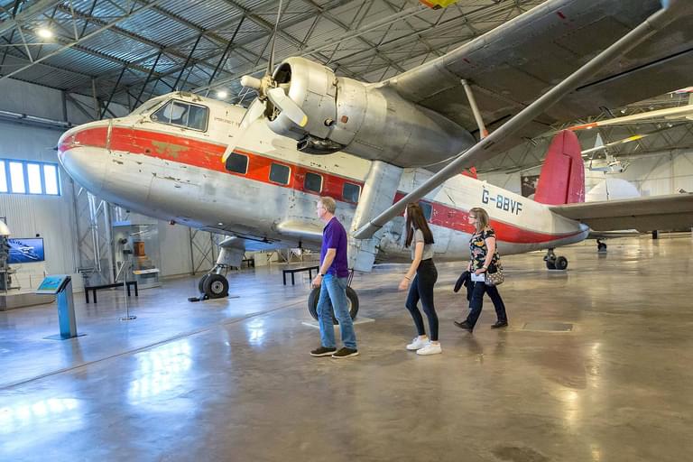 A family walking underneath the wing of a Twin Pioneer aircraft in the Civil Aviatio hangar.