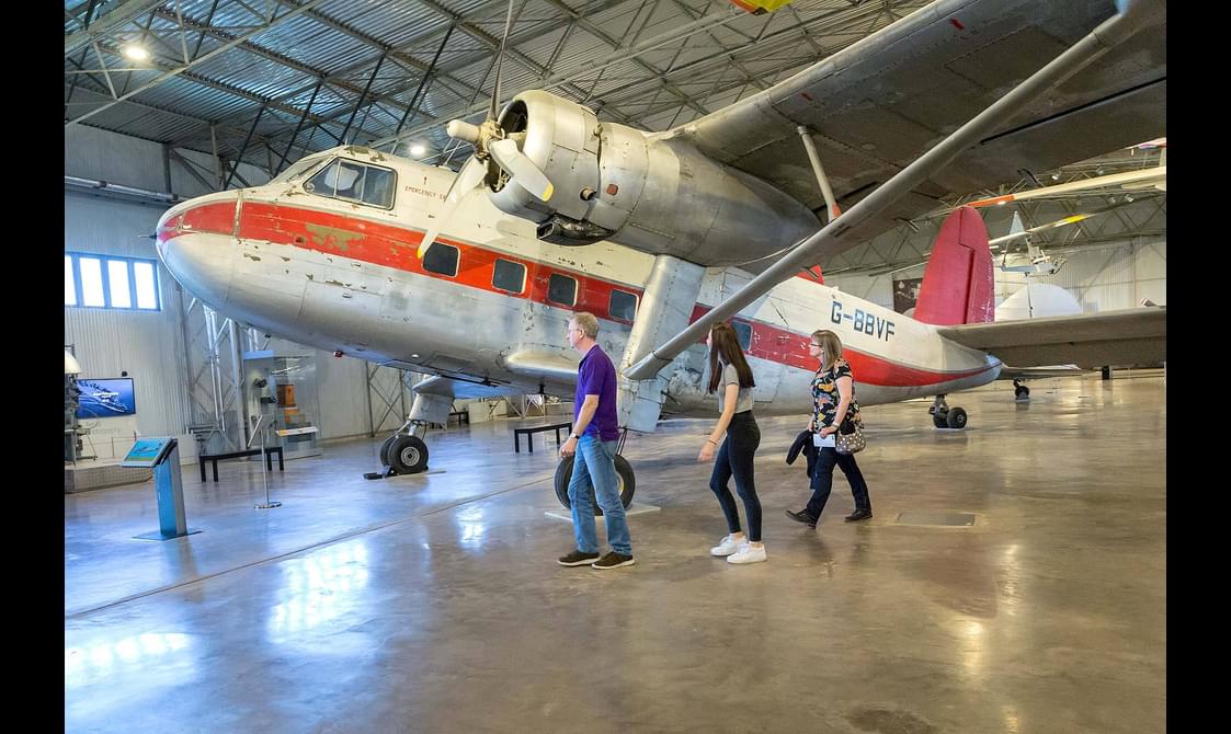A family walking underneath the wing of a Twin Pioneer aircraft in the Civil Aviatio hangar.